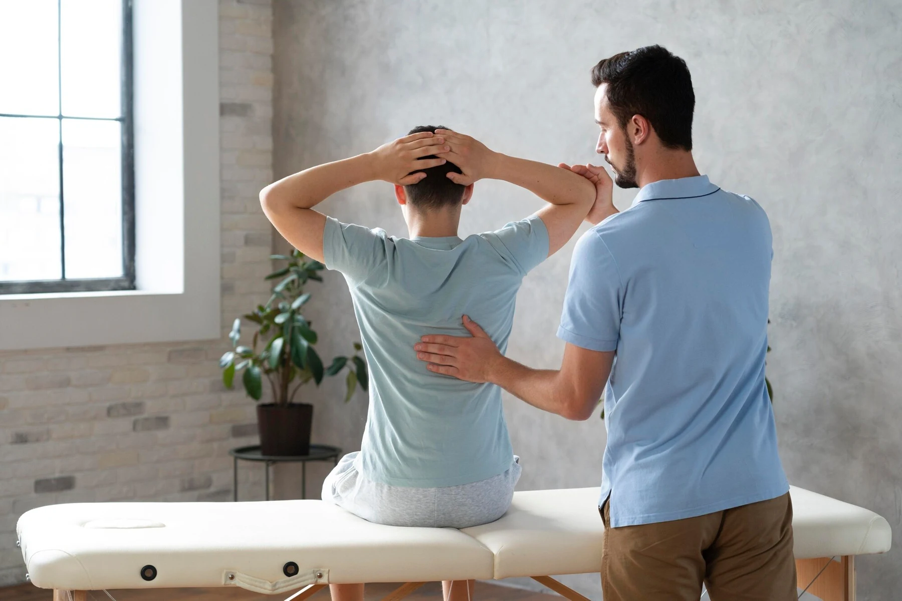 Clinician assessing a seated patient’s shoulder and upper-back movement