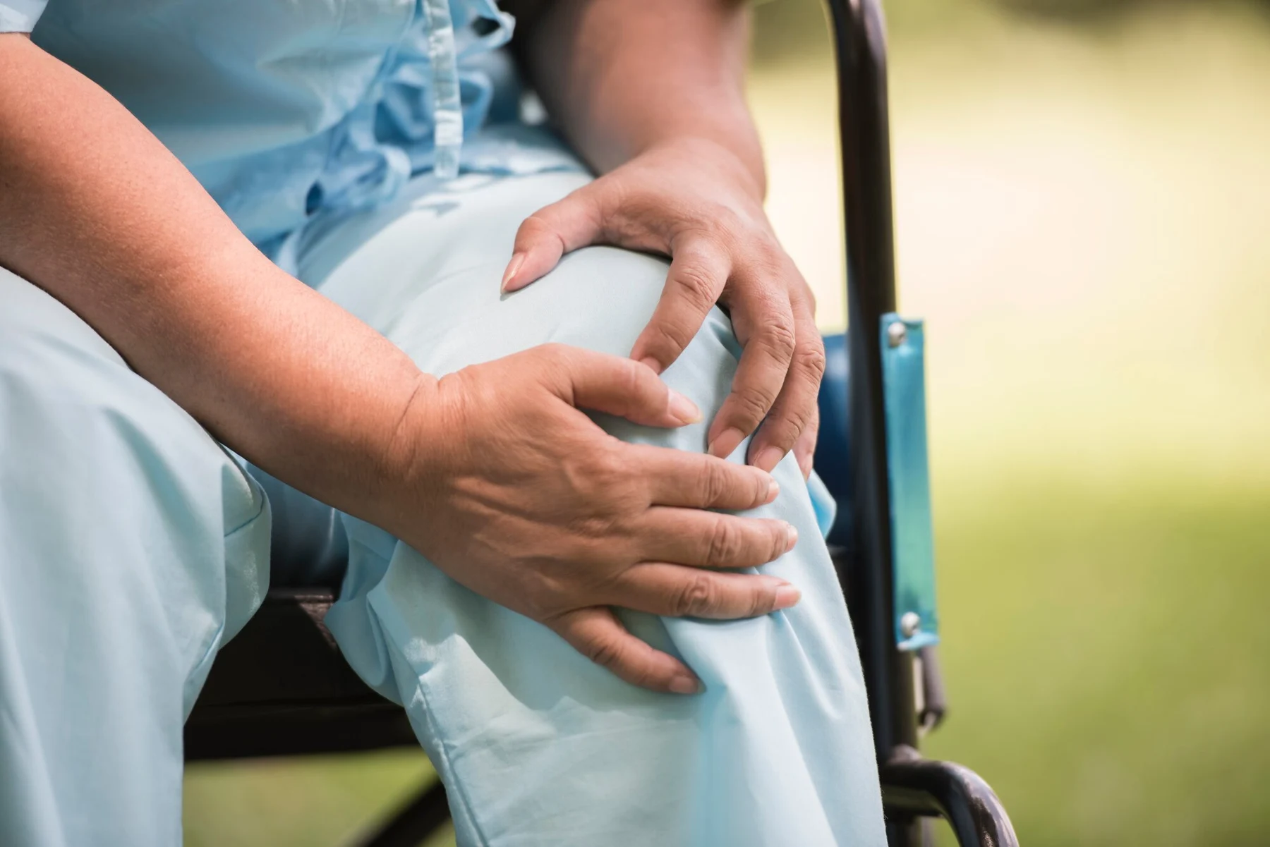Person seated with both hands around a knee