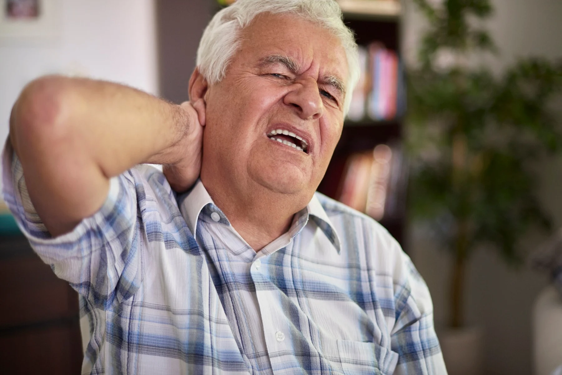 Man holding the back of his neck in discomfort